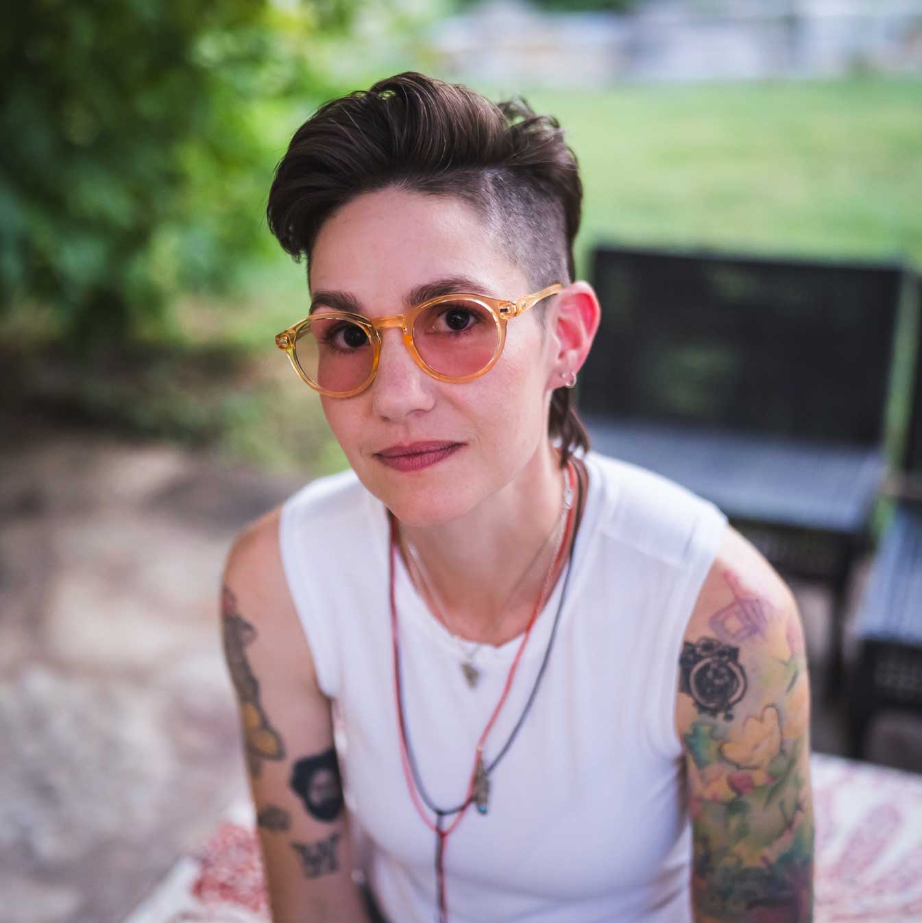 Emily McLoud smiling wide under tree, sunglasses, relaxed summer portrait