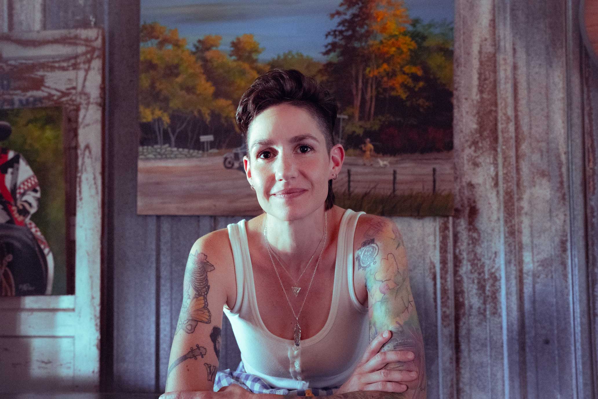 Emily McLoud Americana singer-songwriter smiling in rustic bar with Texas flag, Austin Texas