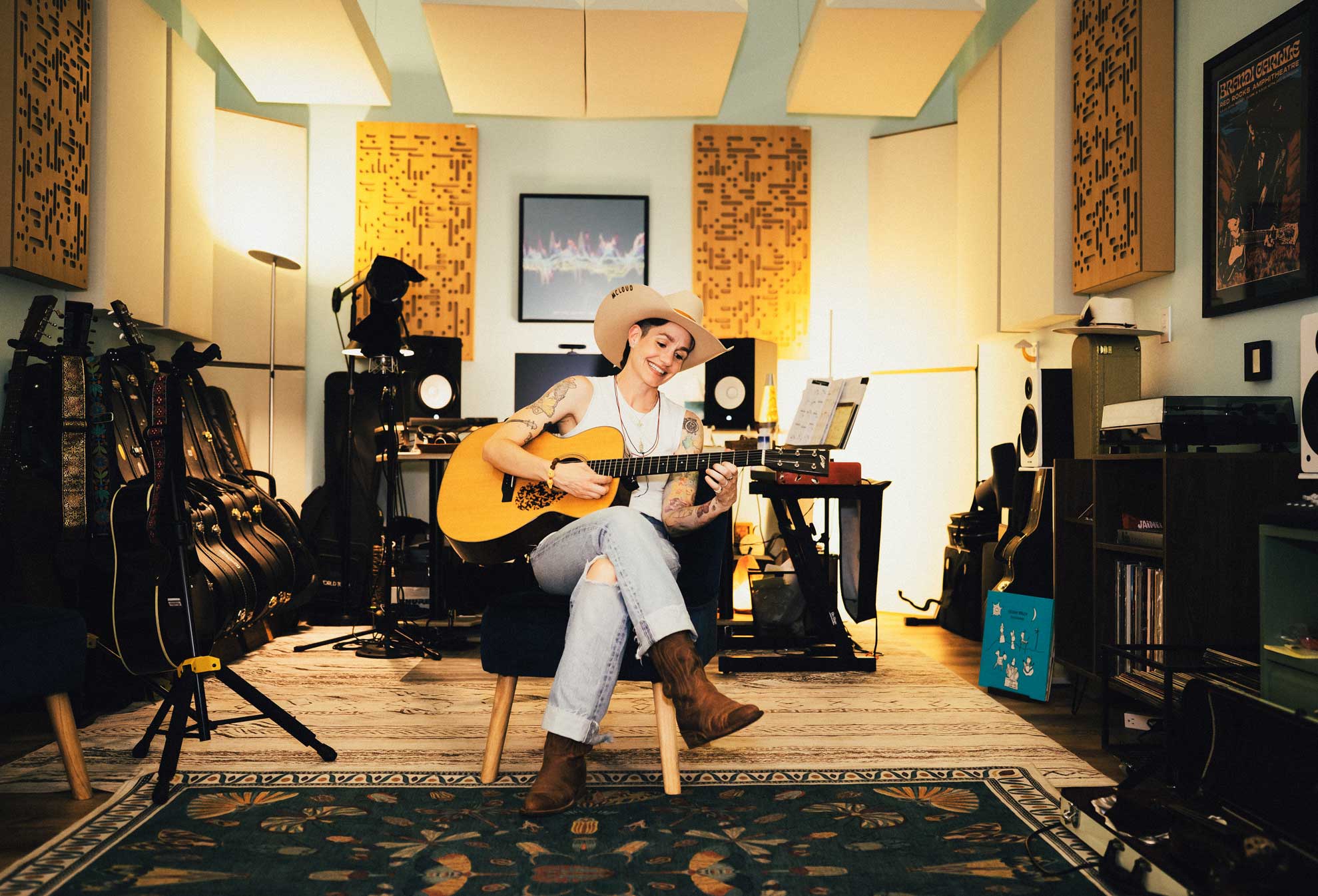 Emily McLoud in recording studio, cowboy hat and guitar, wide shot with full studio view