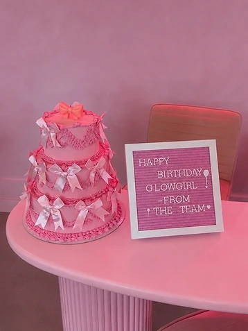 A pink birthday cake and letter board celebrating at Glowgirl Café