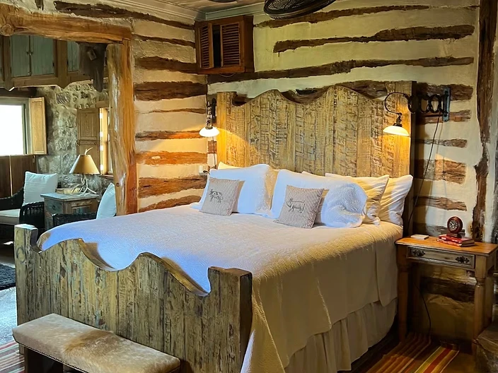 Private bedroom with a hand-hewn wooden headboard at Camp Milagro retreat property in New Braunfels, Texas