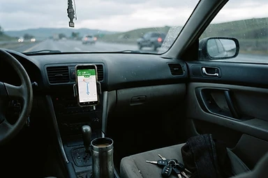 A car interior at early morning, keys and phone on the dash. The in-between moment of heading somewhere.
