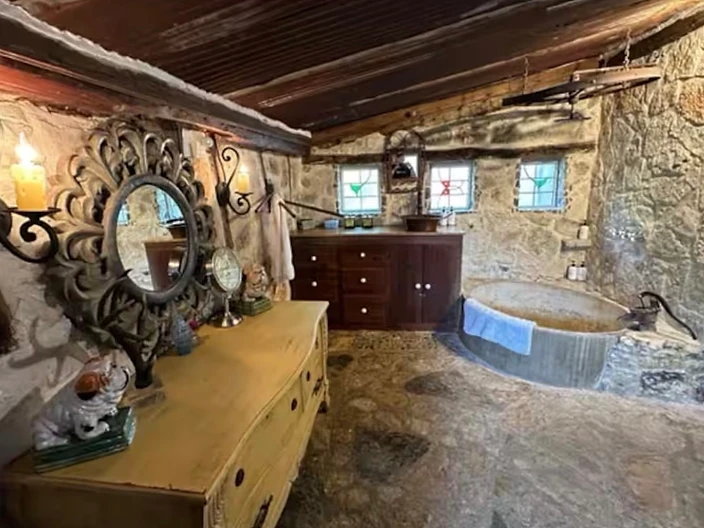 Bedroom dresser with mirror and adjacent stone bathroom at Camp Milagro