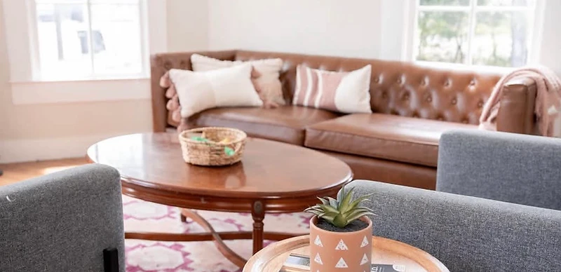 Detailed view of the New Braunfels therapy office, with a round side table holding a succulent and book beside two armchairs and a leather sofa.