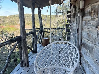 Covered porch with hanging chairs overlooking the Texas Hill Country at Camp Milagro