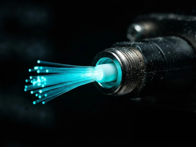 Dettaglio macro di un connettore in fibra ottica illuminato di ciano