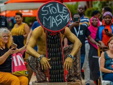 A gold-painted street performer entertaining a crowd in a Kigali public square