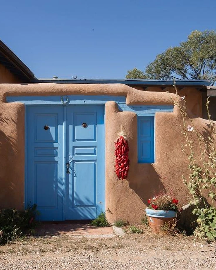 Southwestern adobe building with blue doors and a hanging chili ristra in New Mexico