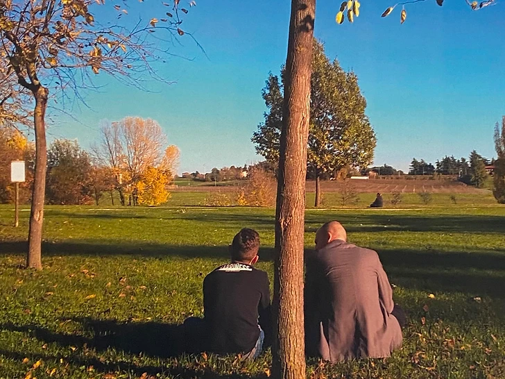 Studente e insegnante seduti sotto un albero in autunno