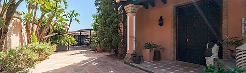 Wooden entrance framed by plants and palms