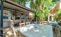Stone barbecue and mosaic table under the porch
