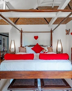 Dark wood four-poster bed with red accents