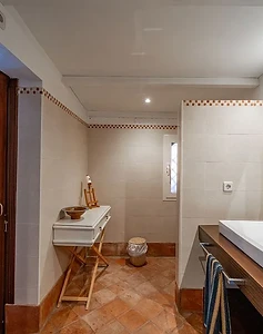 Bathroom with wooden vanity and frameless mirror