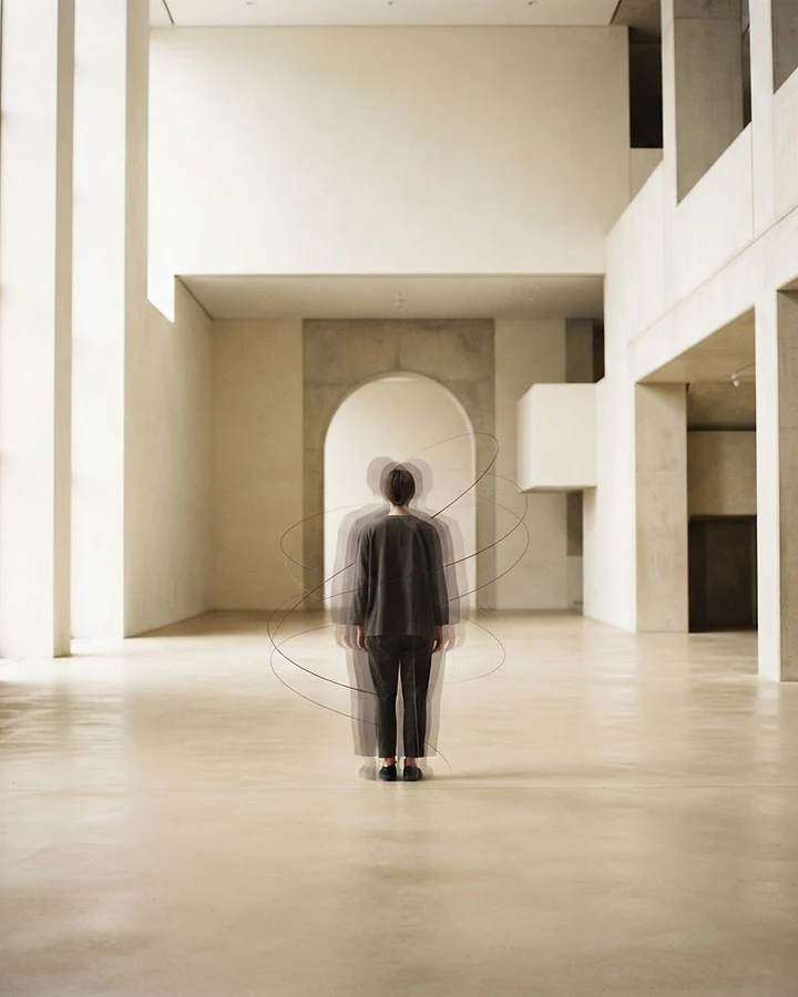 A solitary figure surrounded by translucent layered silhouettes and fine gravitational arcs — the many dimensions within a single person.