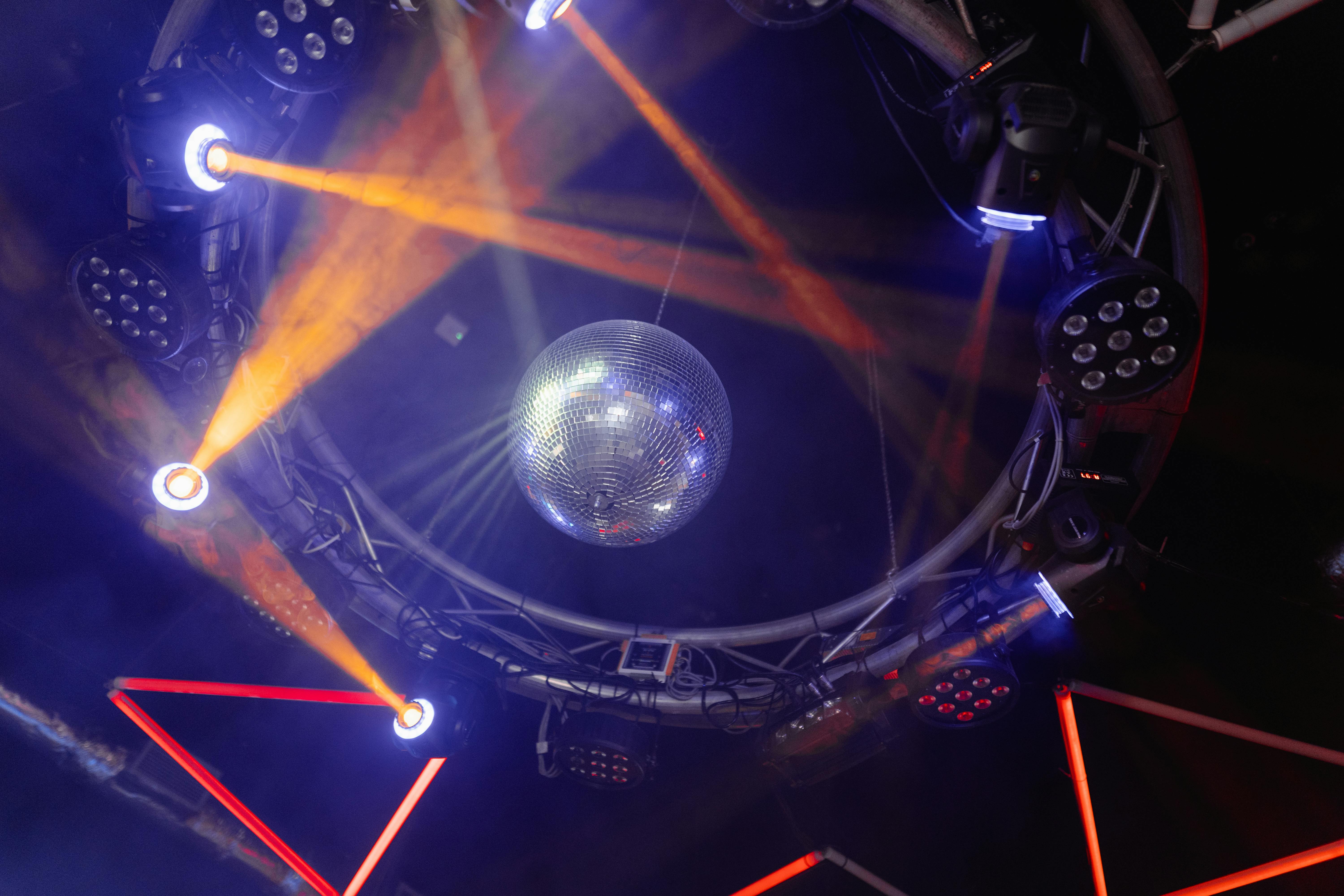 Circular lighting truss with a disco ball and orange stage light beams