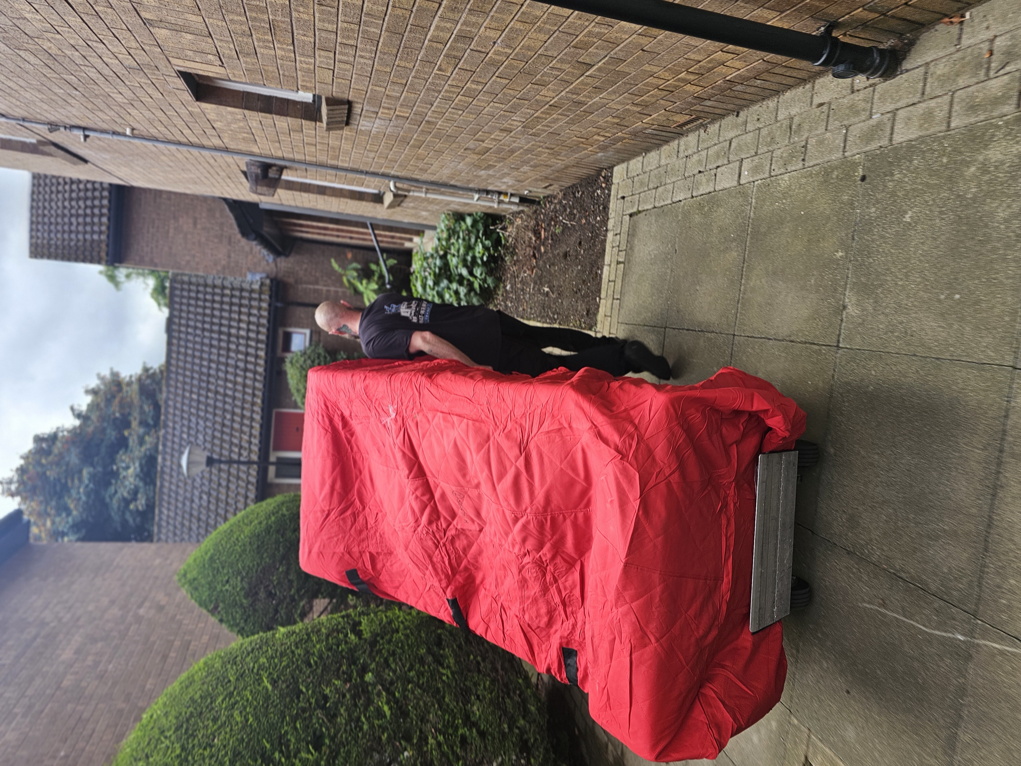 Sofa in red protective cover being transported on a trolley