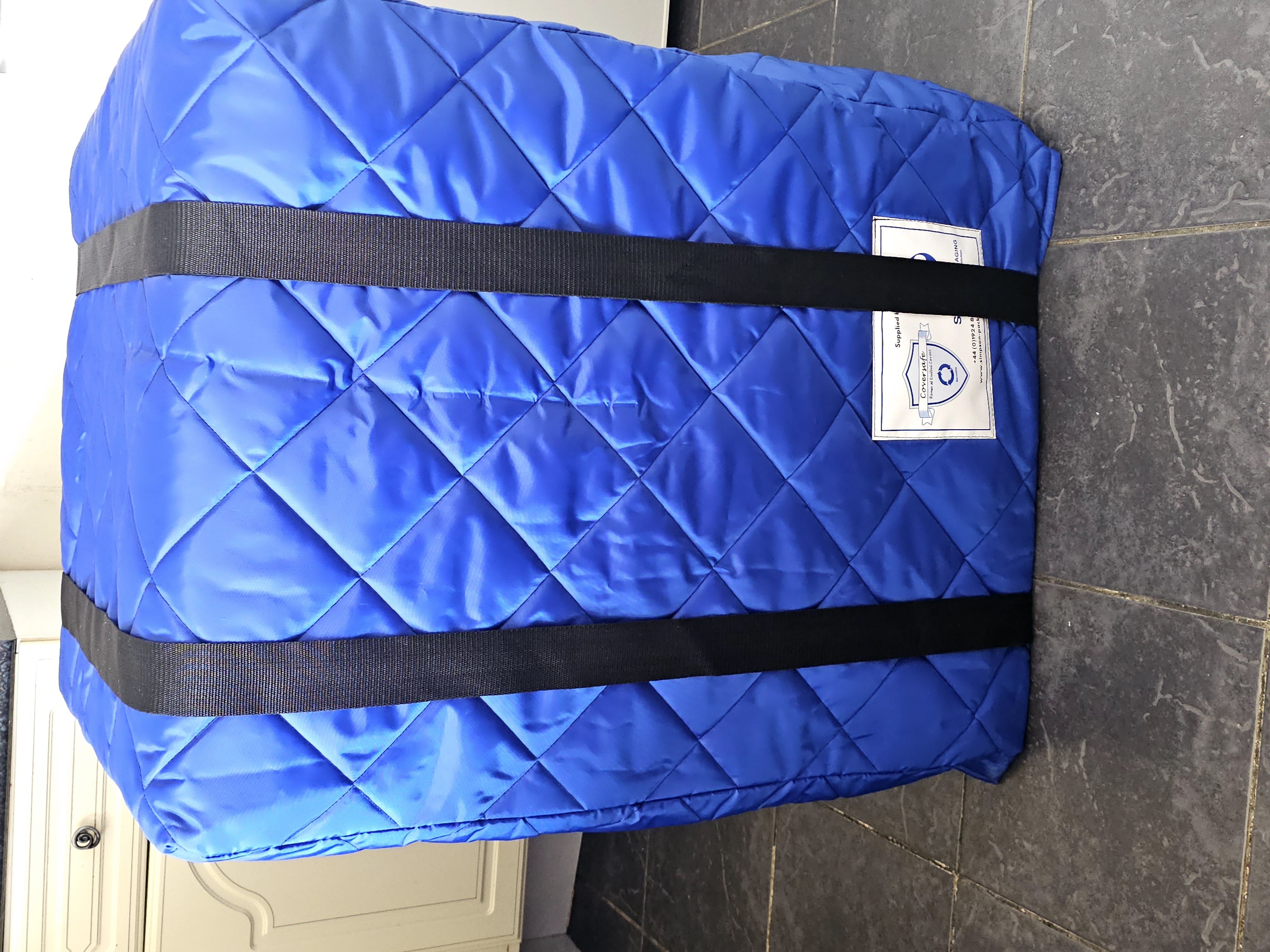 Appliance in blue quilted protective cover secured with straps