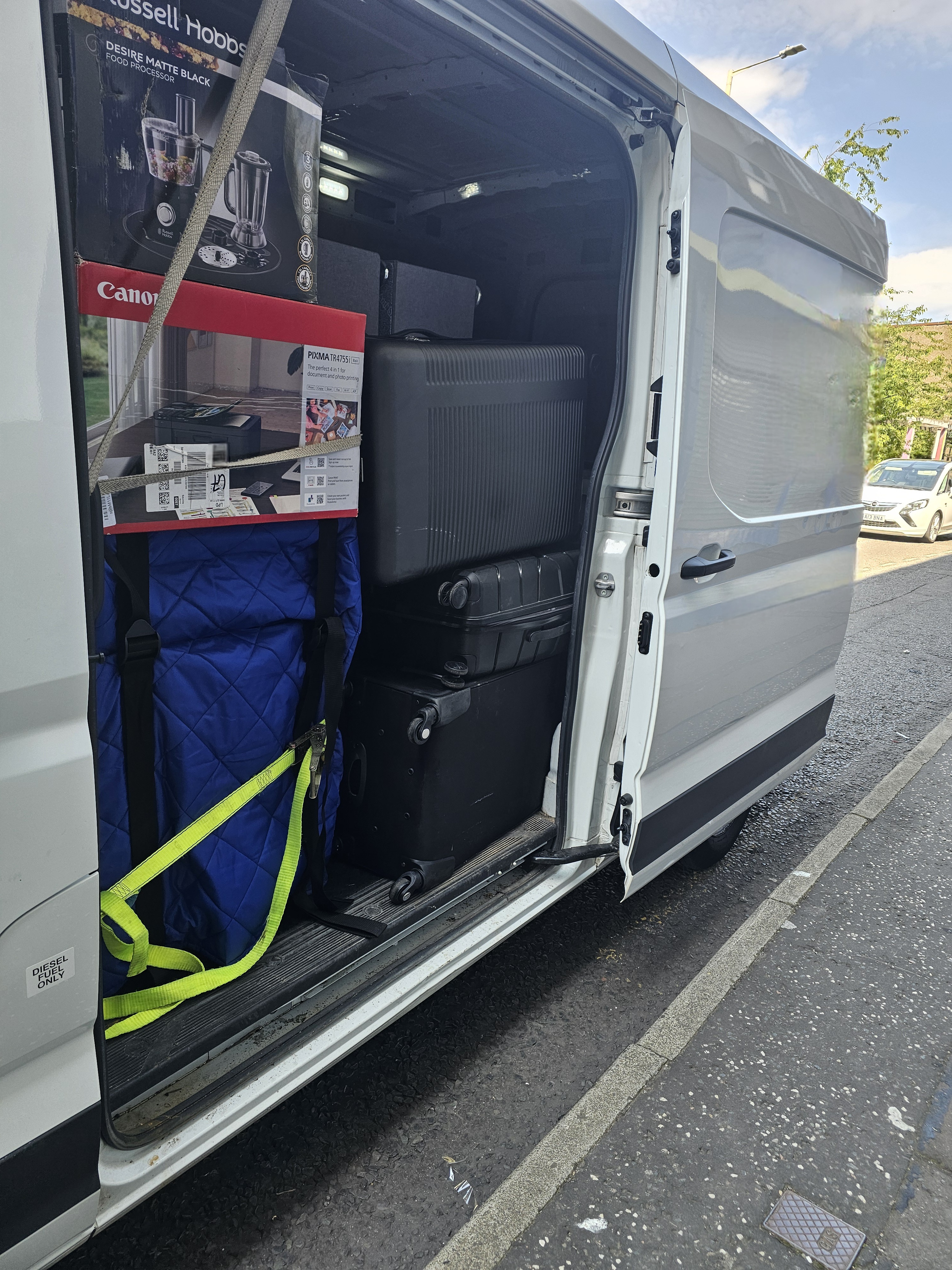 Van side door open with items secured inside using straps
