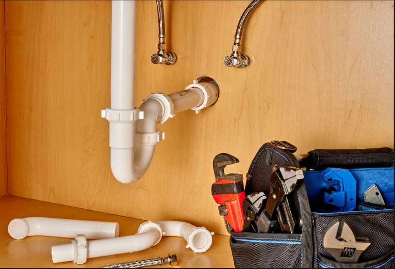 Plumbing installation under sink with PVC pipes and supply lines