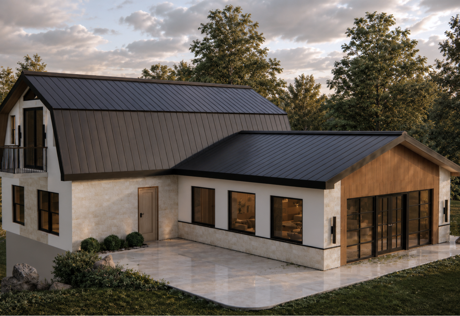 Side-rear exterior view of the guest house with an asymmetrical black standing-seam roof, white stone masonry walls, vertical wood siding, a two-storey section with a small balcony and a single-storey wing with black-framed windows on a stone patio