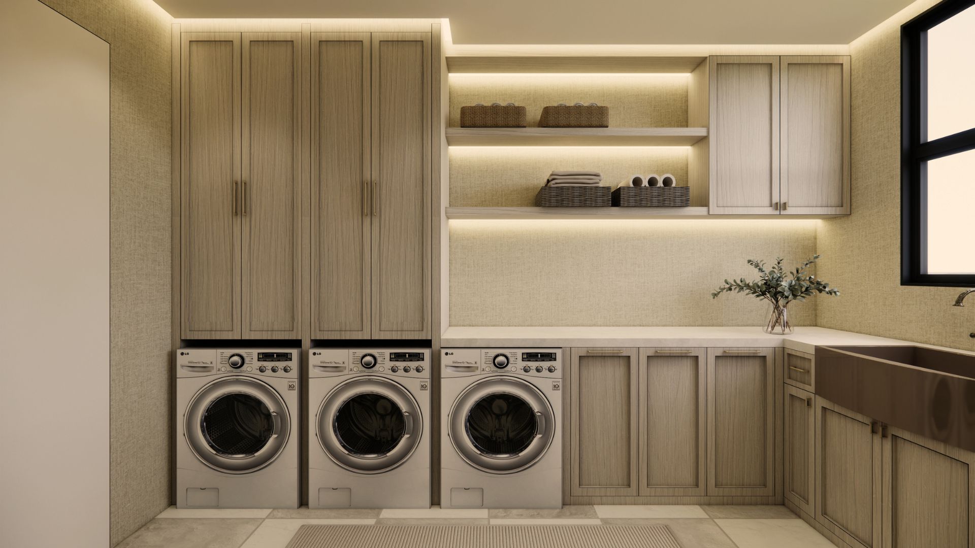 Laundry room in pale oak shaker joinery with three front-loading machines, LED-lit open shelving with baskets and towels, a stone worktop and a bronze farmhouse sink beside a black-framed window