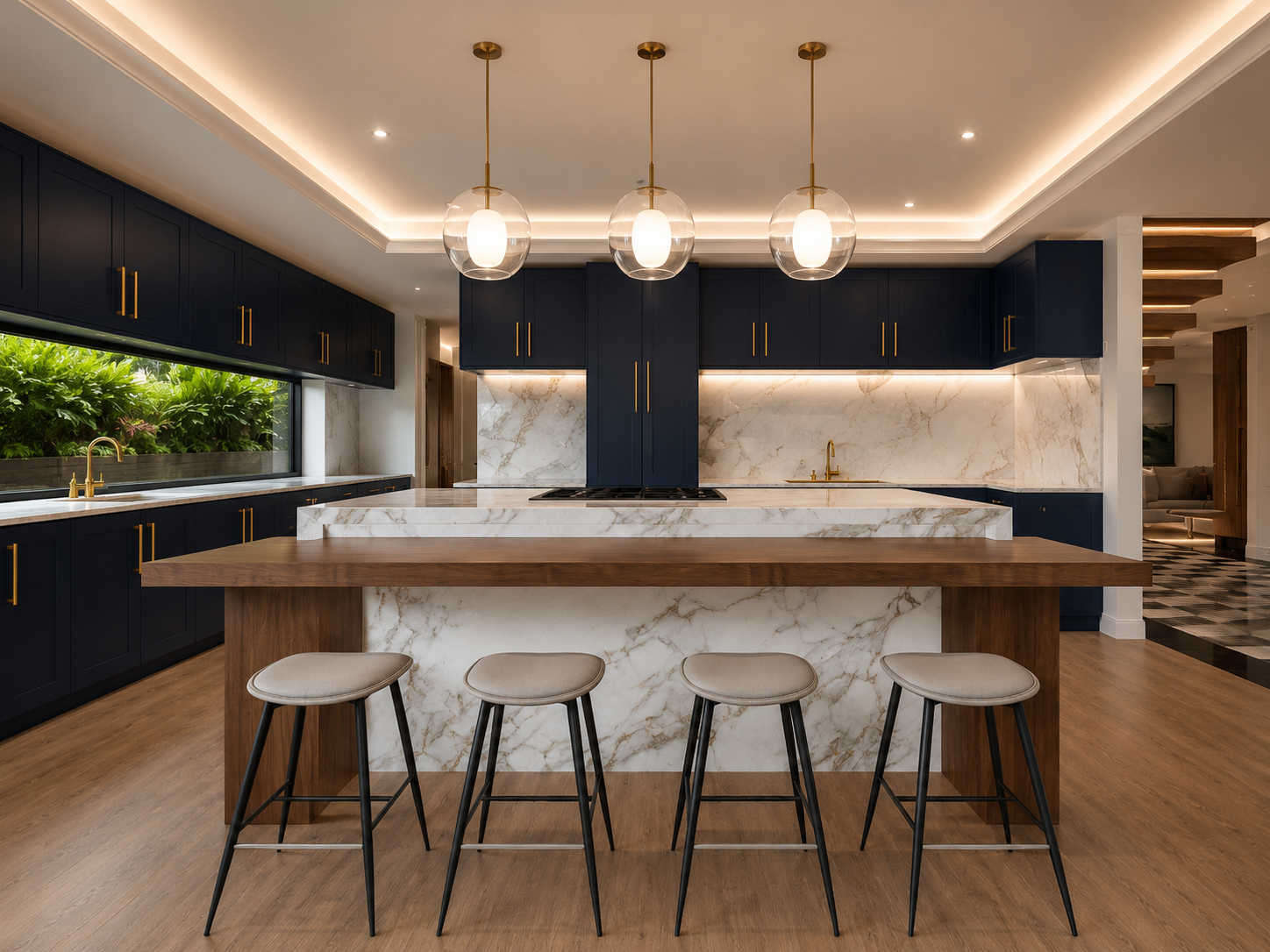 Kitchen in navy shaker cabinetry with slim brass pulls, a marble island and walnut breakfast counter, upholstered stools, ribbon window onto planting and three clear glass globe pendants