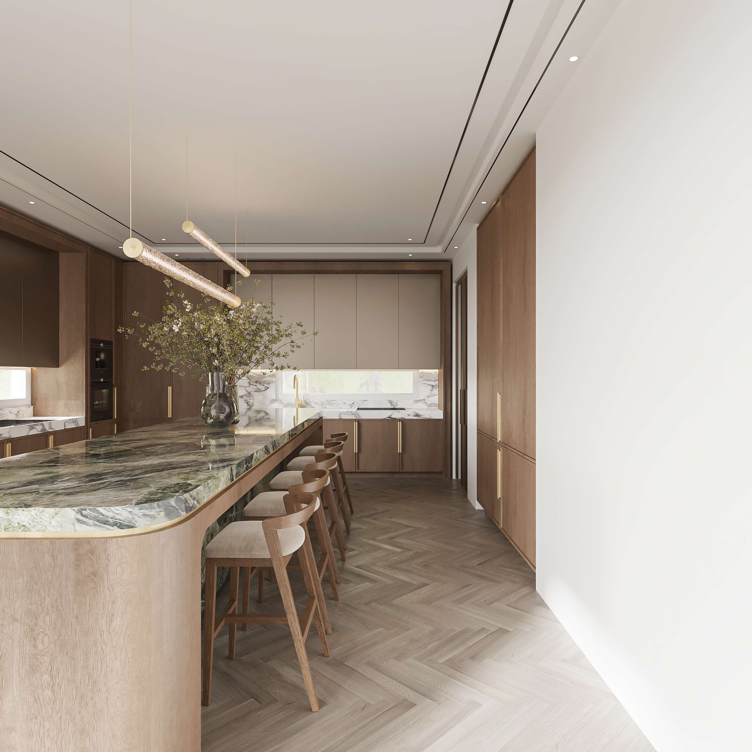 Kitchen island in travertine with a veined green marble top and brass edge, timber bar stools along its length, oak and taupe cabinetry beyond and linear brass pendant lighting