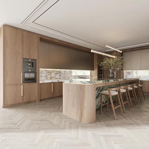 Pale oak kitchen with a curved travertine island, green marble countertop with brass edge and linear pendant lighting above herringbone floors