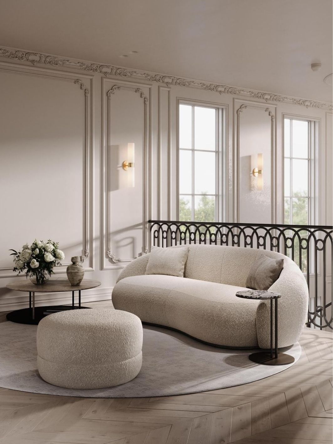 Landing lounge with a curved ivory boucle sofa and round ottoman, ornate plaster panelling with brass sconces, a stone side table with white roses and the ironwork balustrade behind