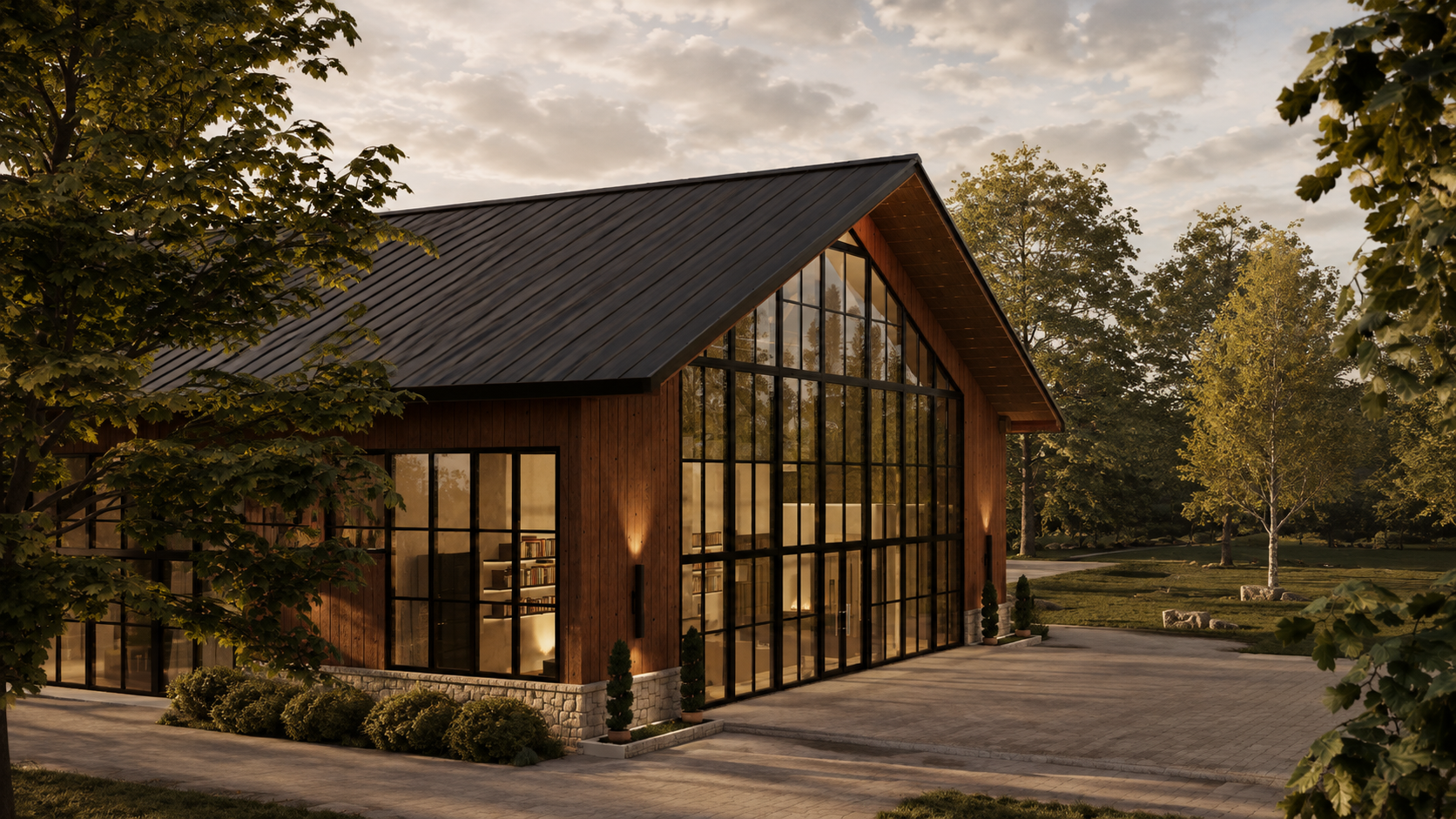 Eye-level front elevation at sunset with a massive black-framed glass gable wall, warm interior fireplace and bookshelves visible through the glass, vertical timber siding, stone base and golden-hour foliage either side