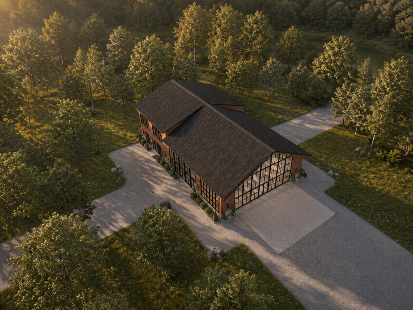 Aerial dusk view of the building's dark gabled roof and full-height gridded glass gable among mature trees, with a gravel path and paved forecourt below