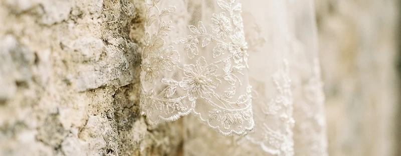 Lace bridal veil against the stone exterior of Dovecliff Hall, a Staffordshire wedding venue