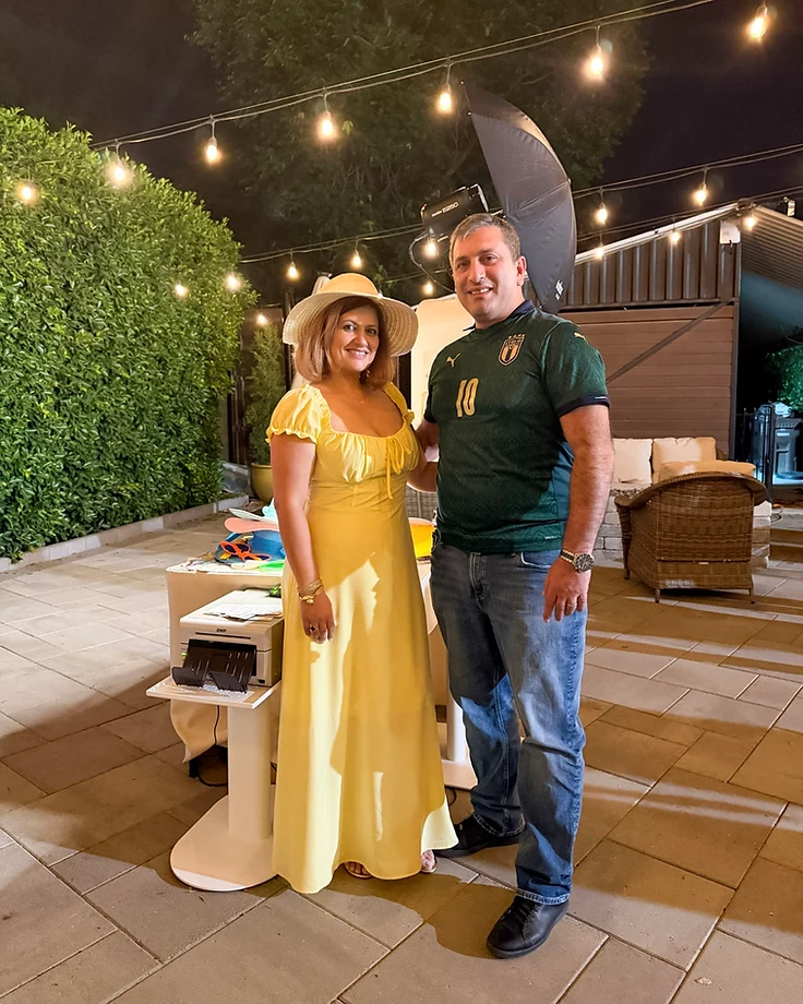 Meri and Tiko beside a GlamBooth photo booth setup at an event.