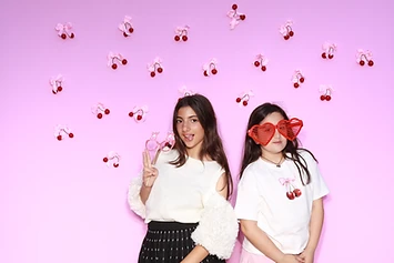 Two girls with heart-shaped glasses at a GlamBooth birthday