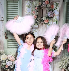Two girls with feather fans at a GlamBooth garden-themed birthday