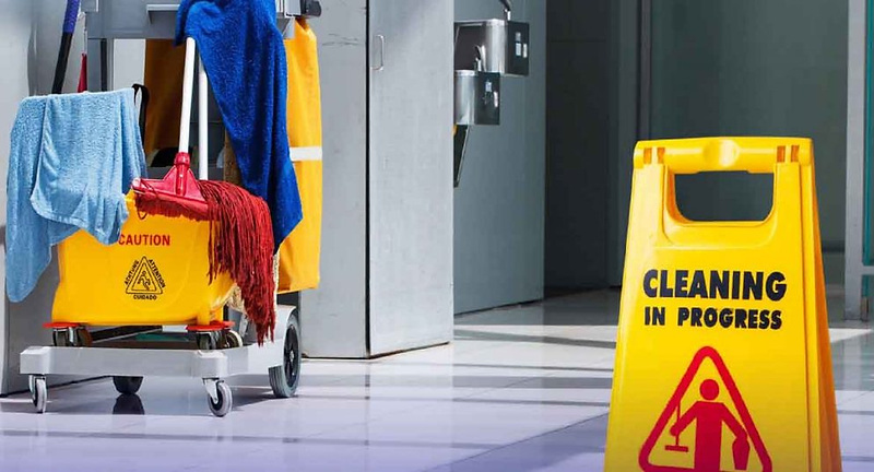 Janitorial cart and cleaning-in-progress sign in a polished office hallway