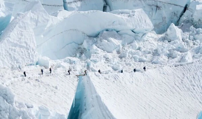 Rope team crossing a ladder over a crevasse on the glacier