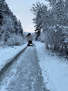 Nathan mid-jump on a snowy path between evergreens