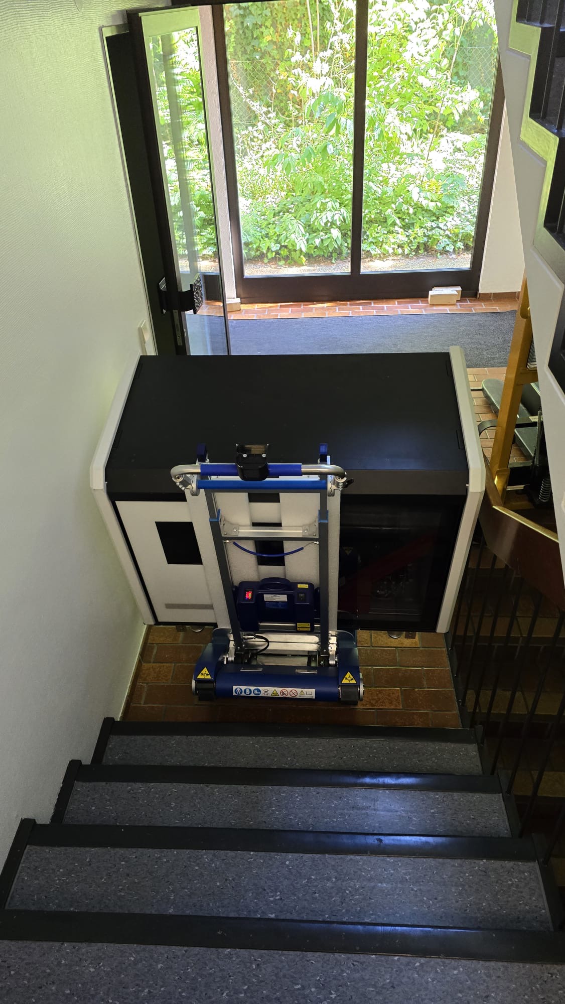Specialized medical equipment transported down stairs using an electric stair climbing trolley.