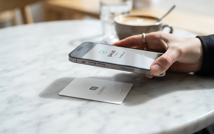 Smartphone approché d'une carte NFC TapRevio sur une table