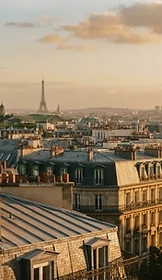 Paris rooftops at golden hour, zinc roofs in warm hazy light