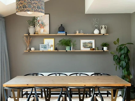 Dining area with floating shelves against a sage-green wall