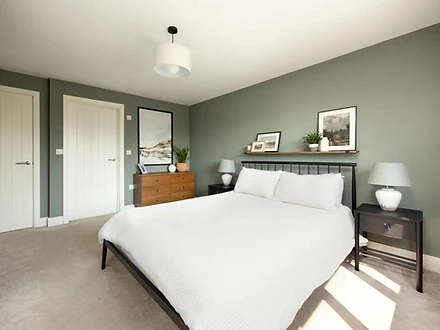 Master bedroom with black metal bed frame and sage-green walls