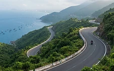 Hai Van Pass mountain road winding along the coastal cliffs above Da Nang Bay with the ocean visible below
