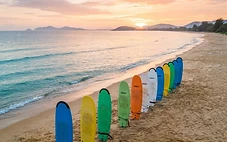 Beginner surfing in Da Nang with soft-top boards on My Khe Beach at sunrise