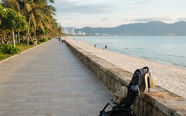 Da Nang beach in the morning light with a stroller parked on a flat promenade path near the shoreline