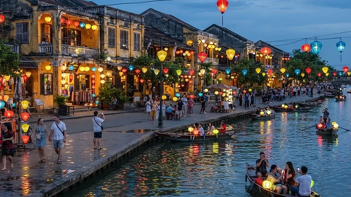 Hoi An's lantern-lit riverside old town at dusk, with wooden boats on the Thu Bon River and warm yellow buildings.