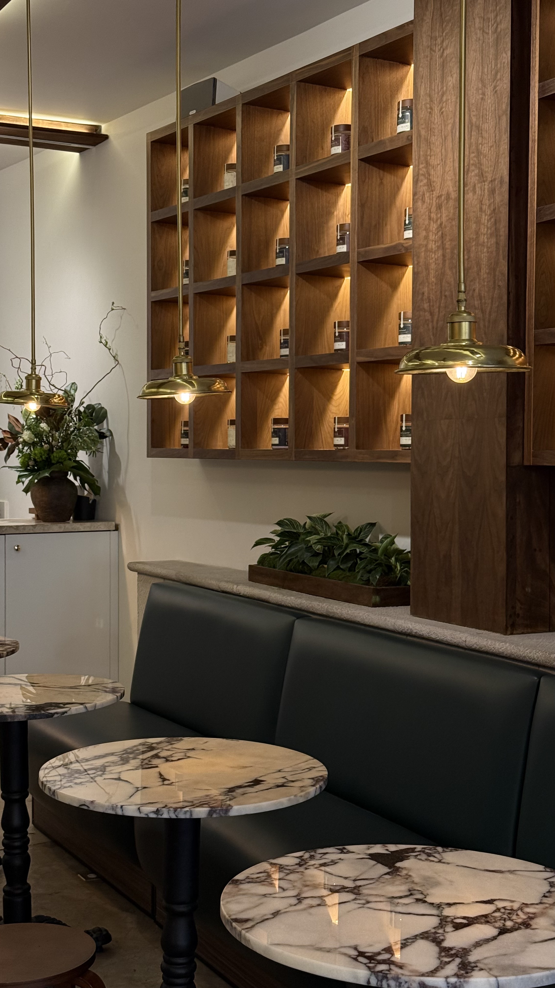 OXOMIO boutique seating and walnut display wall with brass pendant lighting