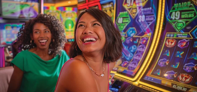 Guests enjoying the bright, colorful slot machines in the Carnival cruise casino