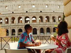 Travelers enjoying drinks with the Roman Colosseum in the background